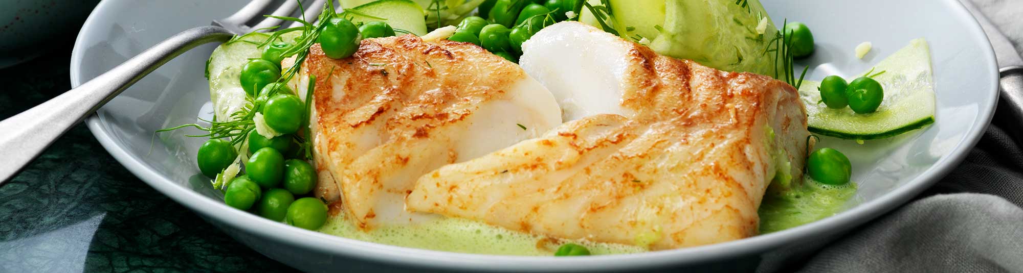 Smörstekt torskrygg serverat med ärter, gurka och sås