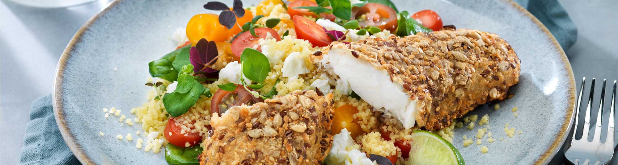 Panerade fiskfiléer serverat med en fräsch couscoussallad toppat med rostade frön