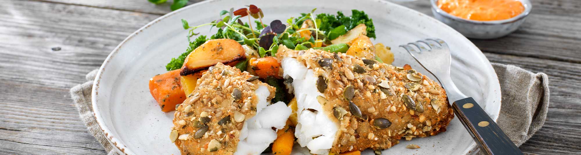 Panerade fiskfiléer med ugnsrostade grönsaker och örtsås